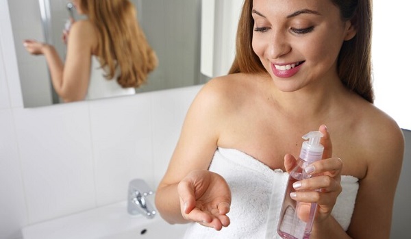 3 produits à changer pendant la grossesse: photo d'une femme en serviette blanche et tenant un produit cosmetique.