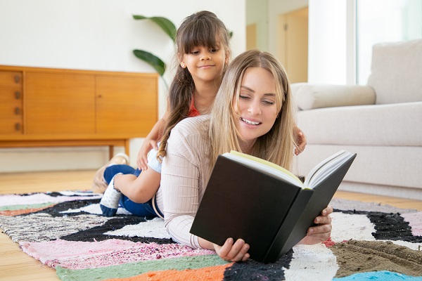 6 conseils pour rendre la lecture amusante pour les enfants,
petite fille assise sur le dos de sa mère, regardant un livre