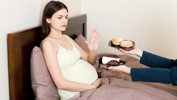 Brûlures d'estomac pendant la grossesse : Apprivoiser la flamme: photo d'une femme enceinte refusant de manger des gâteaux.