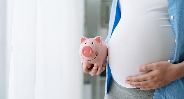 Devenir un meilleur dépensier avant l'arrivée de bébé: photo d'une femme enceinte tenant une tirelire rose