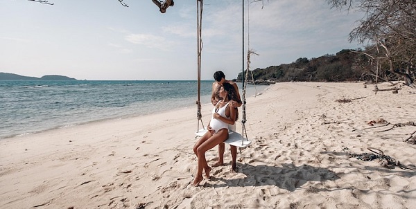 En parfaite harmonie: photo d'une femme enceinte en maillot blanc assise sur une balançoire à la plage.