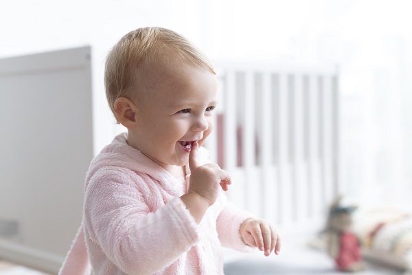 La dentition du bébé:  votre guide, bébé sourit, main dans la bouche
