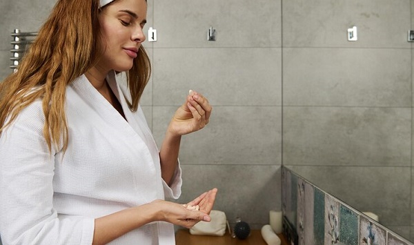 Les nutriments en un mot: photo d'une femme en peignoir blanc tenant des cachets.