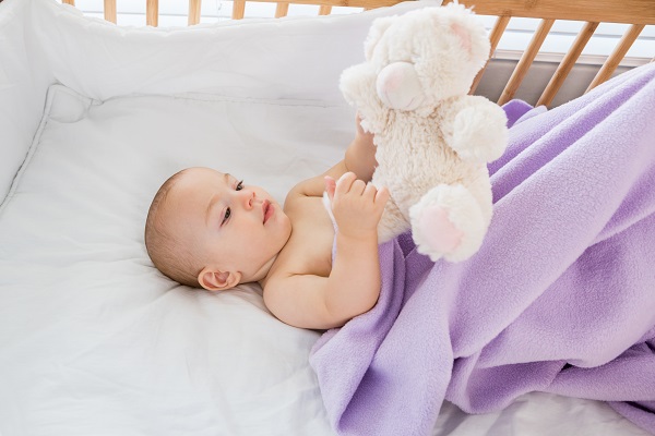 Les principes de base du sommeil en toute sécurité pour les tout-petits; bébé dans le berceau avec ourse en peluche
