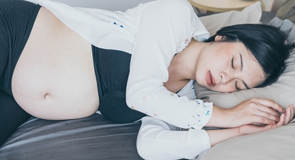 Recette pour le repos: photo d'une femme asiatique, enceinte et en veste blanche en train de dormir