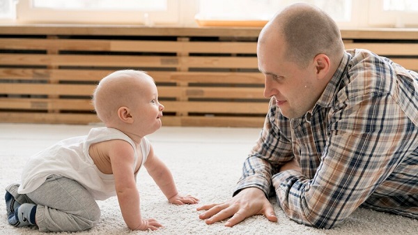 Le babil des bébés est un outil de communication essentiel: bébé à quatre pattes discutant avec son papa.