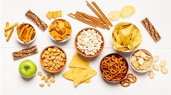 Les meilleurs aliments pour la nausée du matin: photo de plusieurs sortes de snacks avec une seule pomme verte à gauche.