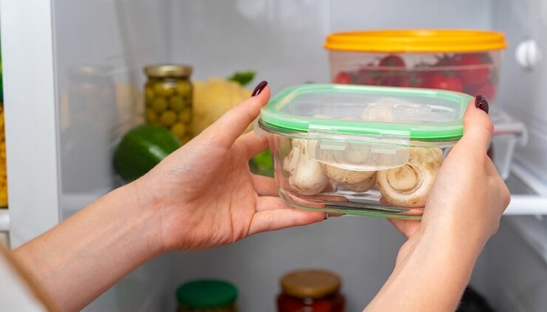 10 produits de base pour votre garde-manger prénatal: photo des mains d'une femme faisant entrer une barquette en verre dans le frigo