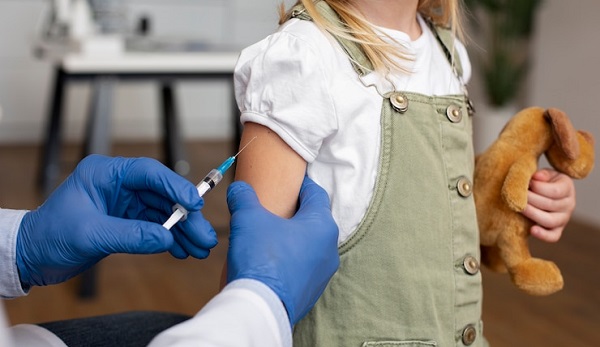 Ce que les parents doivent savoir sur les bloqueurs d'hormones : photo d'une petite fille vaccinée en tenant une peluche.