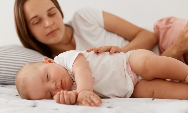 8 signes d'un bébé en bonne santé: photo d'un bébé endormie observé par sa maman